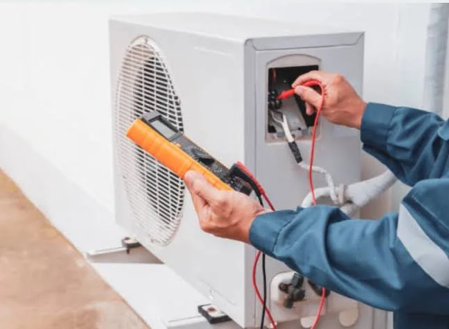 Technician checking electrical controls on HVAC equipment